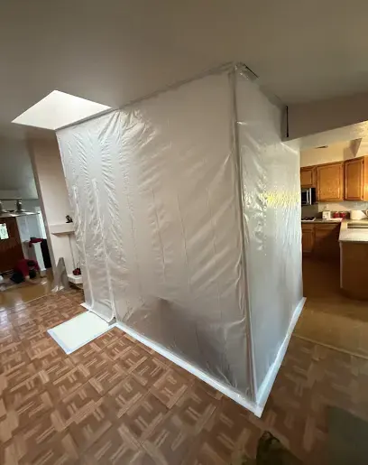 A plastic containment tent set up over a wet floor area in a kitchen