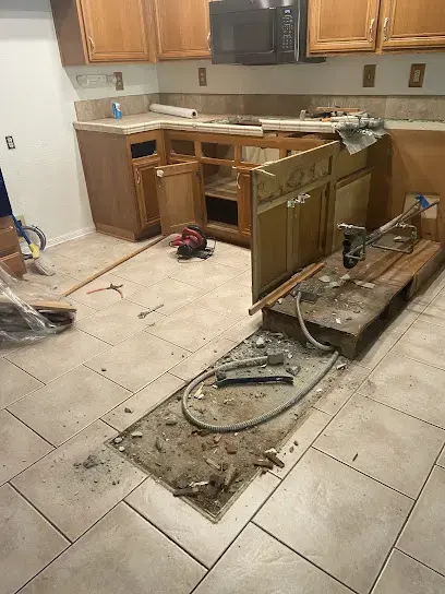 Kitchen flooring pulled up to the slab after a leak under the cabinets