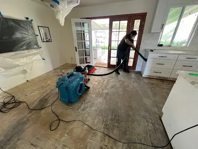 A technician extracting water from a stripped floor with a portable extraction unit