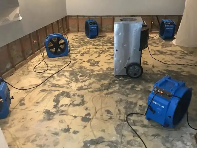 Air movers and a dehumidifier staged on a bare floor for a Highland water damage dry-out